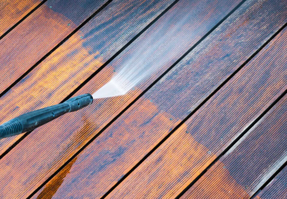 Power washing a wooden deck; a handyman service cleaning and restoring outdoor wood surfaces.