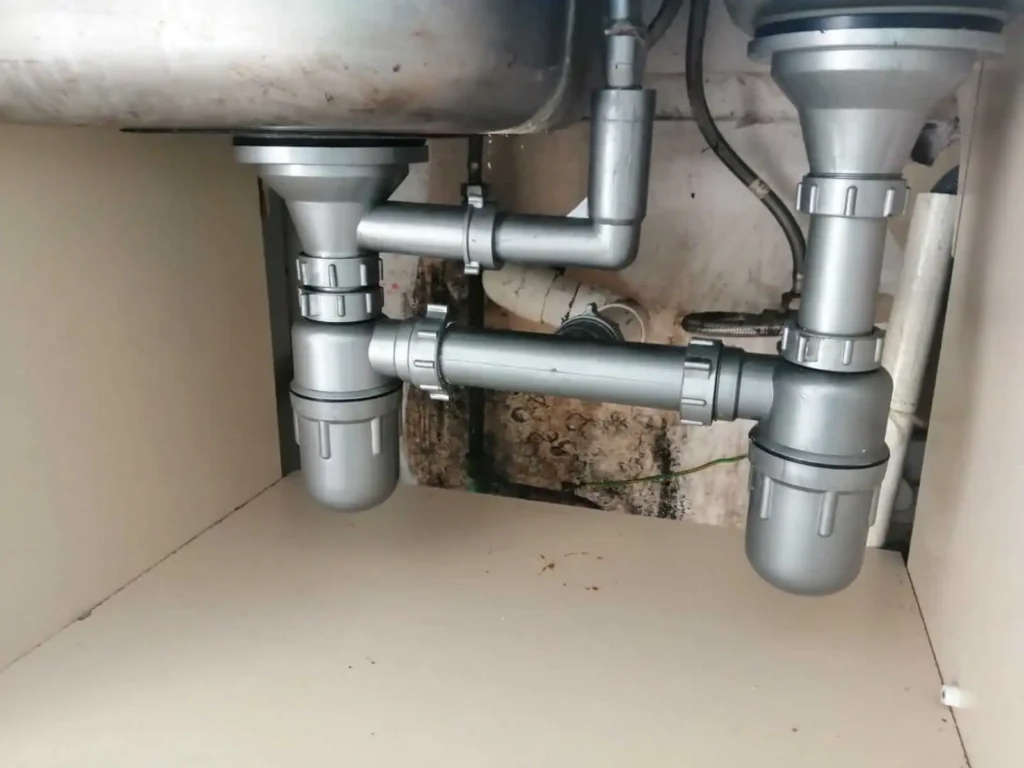 Plumbing under a double sink, showing pipes and traps, a typical handyman job in Dublin.